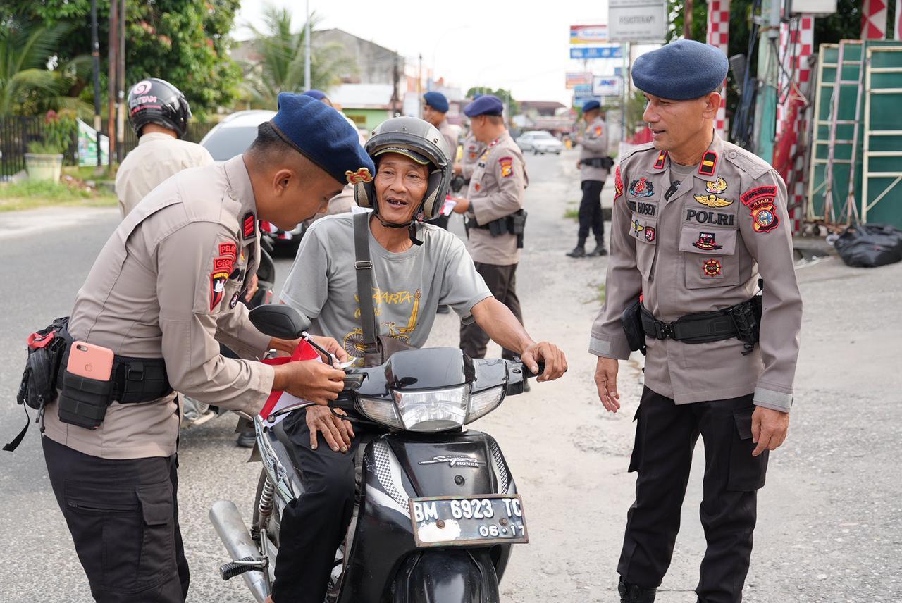 Rayakan HUT RI ke-80, Brimob Polda Riau Bagikan Bendera Merah Putih ke Masyarakat
