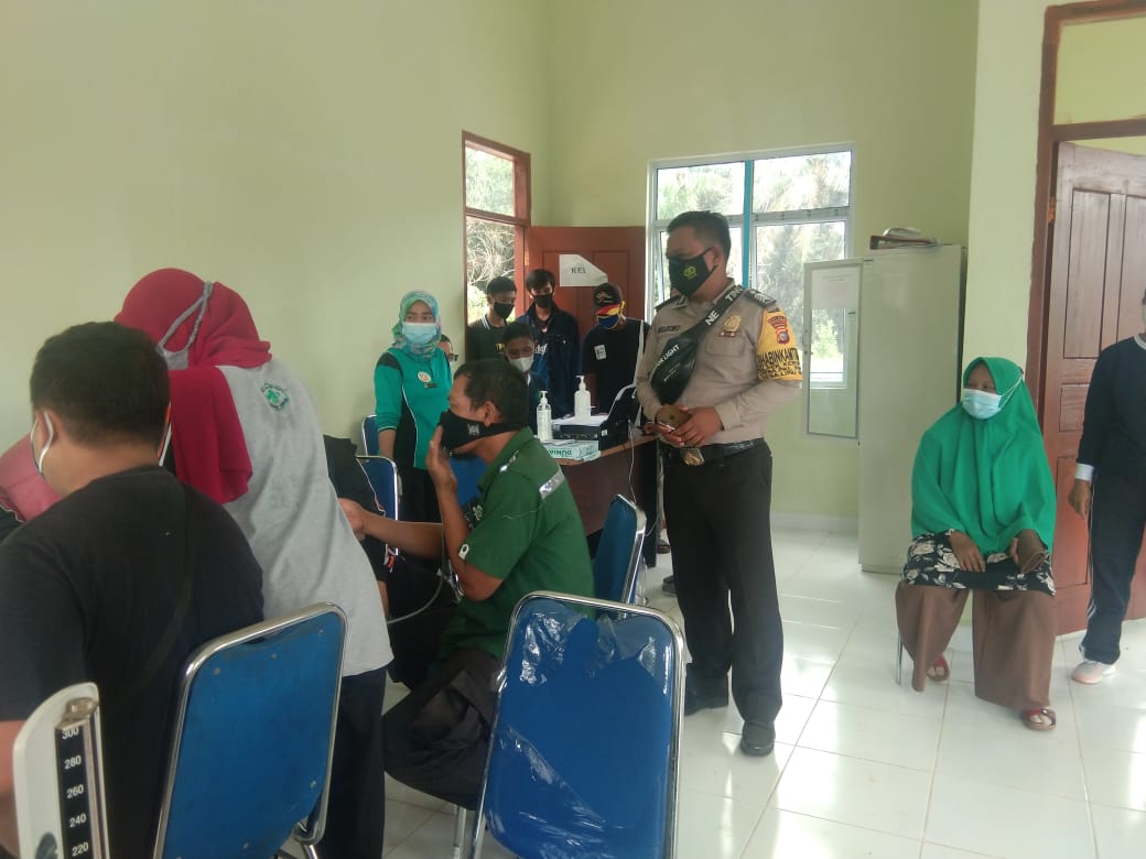 Bhabinkamtibmas, Polsek Kerumutan Dampingi Vaksinasi Warganya di Puskesmas setempat