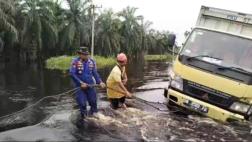 Dua Perwira Bantu Tarik Mobil Box Terperosok di Lokasi Banjir Pelalawan