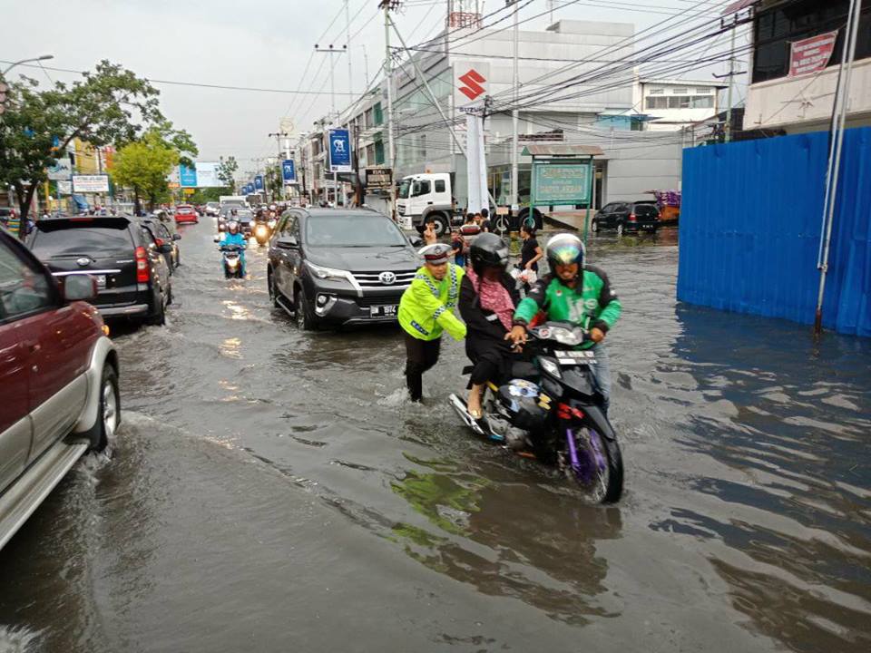 Polantas Bantu Dorong Sepeda Motor yang Mogok Akibat Banjir di Pekanbaru